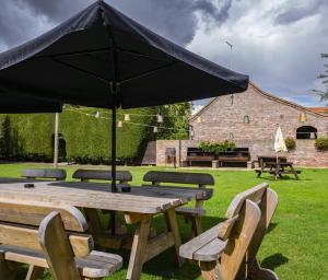 a wooden picnic table with an umbrella in a yard at The Ship`s Quarters in Dunswell