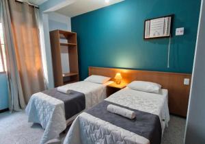 a room with two beds and a blue wall at Pousada Villa Jardim in Silva Jardim