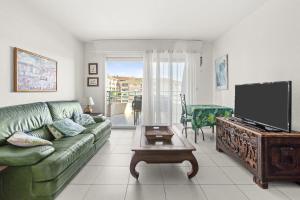 a living room with a green couch and a flat screen tv at Un Air De Venise in Fréjus