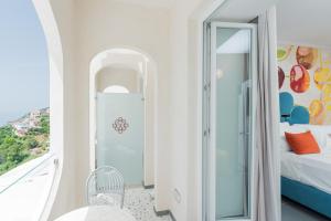 a white room with a bed and a glass door at Albergo Dipinto BaccoFurore in Furore