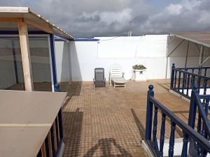 un patio con 2 sillas y una pared blanca en Abdallah Appartement, en Essaouira