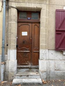 a wooden door in a building with two red doors at Gold, 500 m du centre de Valence in Bourg-lès-Valence