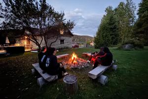 a group of people sitting around a fire in a yard at Chalet du lac avec SPA privé, wifi, BBQ et SUP in Saint Adolphe D'Howard