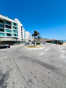 an empty street in front of a building with a palm tree at Suíte Pé na Areia in Arraial do Cabo +3 photos