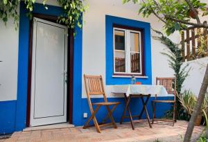 une maison bleue et blanche avec une table et des chaises dans l'établissement CASAZUL Milfontes, à Vila Nova de Milfontes