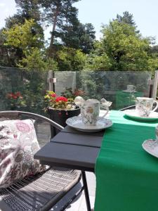 un tavolo con tovaglia verde, tazze e piatti di Gizella apartman a Balatonfenyves