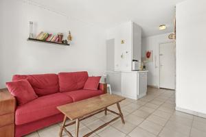 Una sala de estar con un sofá rojo y una mesa. en Appartement à 200 M De La Mer, en Fréjus
