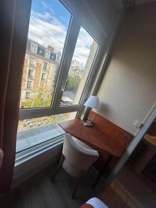 a desk and a chair in a room with a window at Hôtel Victoria in Reims