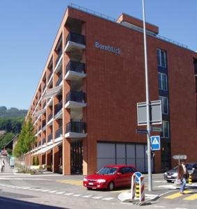 ein rotes Auto, das vor einem roten Backsteingebäude parkt in der Unterkunft Senevita Residenz Bornblick in Olten