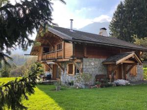 a large wooden house with a green lawn in front of it at Chalet les Champerons - Entre Lacs et Montagne in Marthod