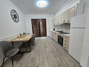 a kitchen with a table and a white refrigerator at Apartament zona ISU Bistrita in Bistriţa