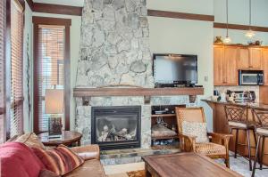 a living room with a stone fireplace with a tv at Stonegate Resort Unit A401 in Big White