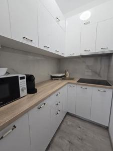 a kitchen with white cabinets and a microwave at Garsoniera zona ISU Bistrita in Bistriţa