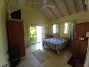 a bedroom with a bed and a sliding glass door at Villa Ora in Calibishie