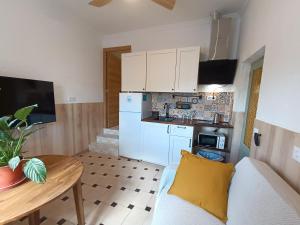 a small kitchen with white cabinets and a table with a couch at Calle Yelmo de Mambrino 19 in Campo de Criptana