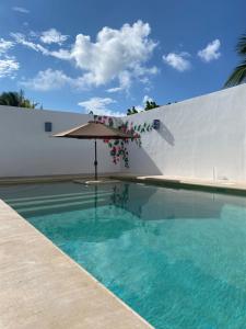 a swimming pool with an umbrella and a swimming pool at Casa Loto A in Chelem