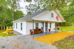 una piccola casa bianca con una bandiera sopra di Downtown Heflin Cottage with Deck and Fire Pit! a Heflin