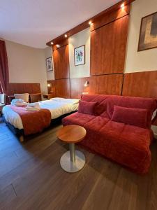a hotel room with a couch and a bed at Hôtel Victoria in Reims