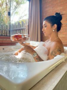 Eine Frau in einer Badewanne mit einem Glas Wein. in der Unterkunft Terra Verde Visconde de Mauá in Visconde De Maua