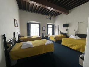a room with three beds with yellow sheets at Hotel Spring in Guatemala
