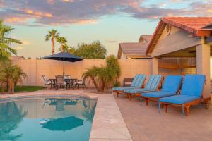 a group of blue chairs sitting next to a pool at Sunny Home with Backyard Oasis in San Tan Valley! in Queen Creek