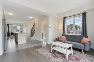 una sala de estar con un sofá y una mesa en A Brand New 4BR Townhouse in Thorold Retreat, en Thorold