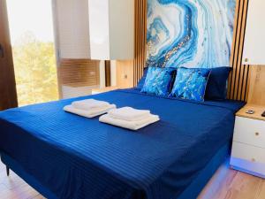 a blue bed with two towels on top of it at Indigo Royale apartman Borovi in Divčibare