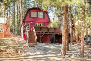 a red house with a deck in the woods at The Lions Den in Big Bear City