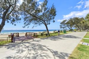 a person walking down a sidewalk next to the beach at The Ocean - Beachfront 72F 3Bedroom Skyhome Ocean Views with Parking & Resort Facilities in Gold Coast