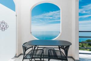 a table and chair on a balcony with a window at Albergo Dipinto BaccoFurore in Furore
