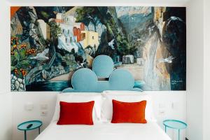 a bedroom with a painting above a bed with red pillows at Albergo Dipinto BaccoFurore in Furore
