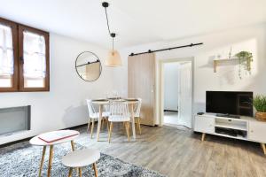 a living room with a table and chairs and a tv at Au nid des remparts à Eguisheim in Eguisheim