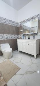 a bathroom with a toilet and a sink and a mirror at Palm Breeze Villa JM in Lucea +39 photos