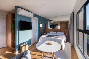 1 dormitorio con 2 camas, mesa y TV en Loft próximo a Vila Germânica e FURB com vaga., en Blumenau