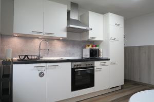 une cuisine blanche avec des armoires blanches et un micro-ondes dans l'établissement Ferienwohnung Loh - 55Zoll TV - Schnelles Internet 500MBit, à Schwäbisch Hall