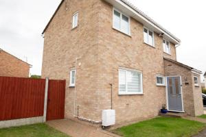 a brick house with a red fence in front of it at Lovely 3 Bedroom House in Chelmsford in Chelmsford