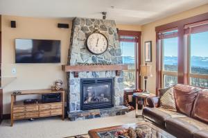 a living room with a stone fireplace with a clock at Stonegate Resort Unit C304 in Big White