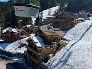 eine Gondel fliegt über ein schneebedecktes Gebäude in der Unterkunft Chalet raffiné à La Tania, Courchevel - 10/12 pers, spa, sauna, billard, ski-in/ski-out - FR-1-575-20 in Courchevel