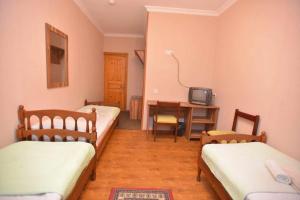 a room with three beds and a desk and a tv at Art House Hostel Aleksandr in Kutaisi