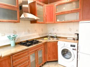 a kitchen with wooden cabinets and a washer and dryer at City Center Stefan street 1 bedroom in Chişinău