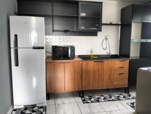 a kitchen with a white refrigerator and wooden cabinets at Sobrado para hóspedes in Guarapuava