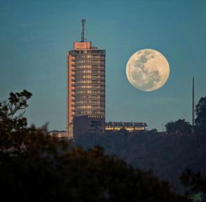 a full moon rising over a building with a skyscraper at Hotel Humboldt in Los Mecedores
