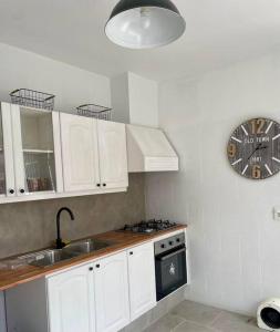 eine Küche mit weißen Schränken und einer Uhr an der Wand in der Unterkunft Casa Figari, Carrasco, divina zona cerca de la rambla in Montevideo