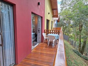 a deck with a table and chairs on a house at Chalé Dália - Recanto Veky in Campos do Jordão