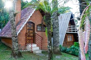 a small brick house with a staircase in front of it at VELINN Pousada Torre Branca in Monte Verde