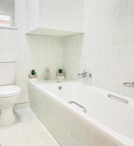 a white bathroom with a tub and a toilet at Sea Sunny View Apartment in Margate +10 photos