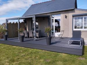 a wooden deck with a chair and a table at La maisonnette in Quinéville