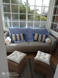 a couch sitting in front of a window with pillows at La maisonnette in Quinéville