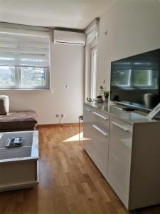a kitchen with white cabinets and a couch at MDM Apartman Vrnjačka Banja in Vrnjačka Banja
