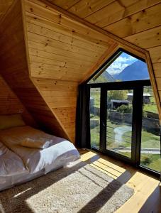 a bed in a room with a large window at Grand Mountain Cottage in Kazbegi